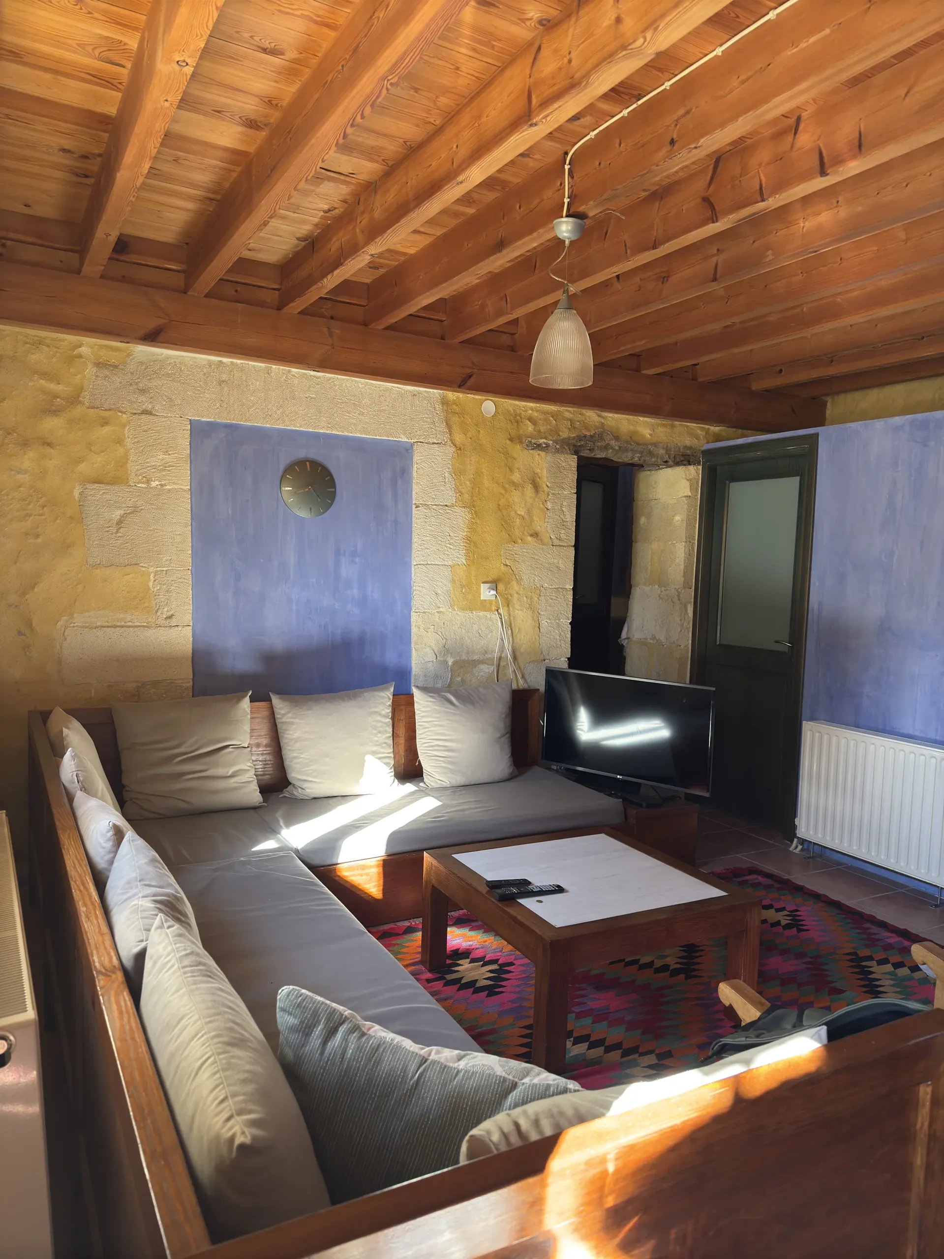 Living room with stone walls, timber ceiling, and kilim rug