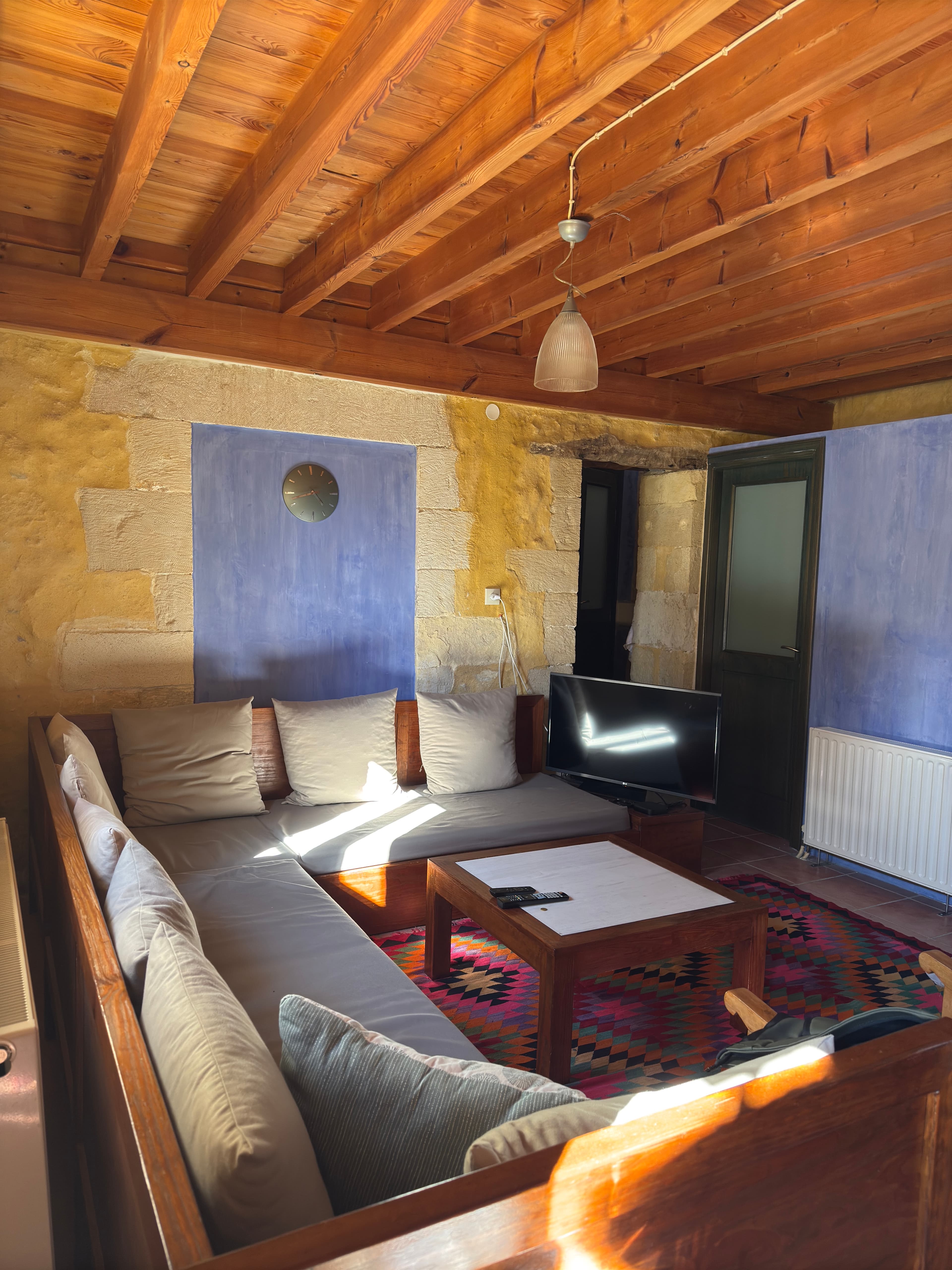 Living room with stone walls, timber ceiling, and kilim rug